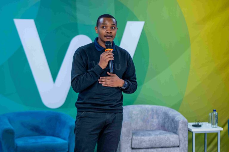 Godlisten Shayo, Head of Customer Engagement at Watu Kenya speaking at Watu Credit event with branded backdrop