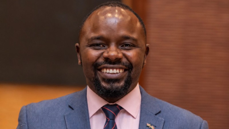 Eric Kinaga smiling in a suit and striped tie