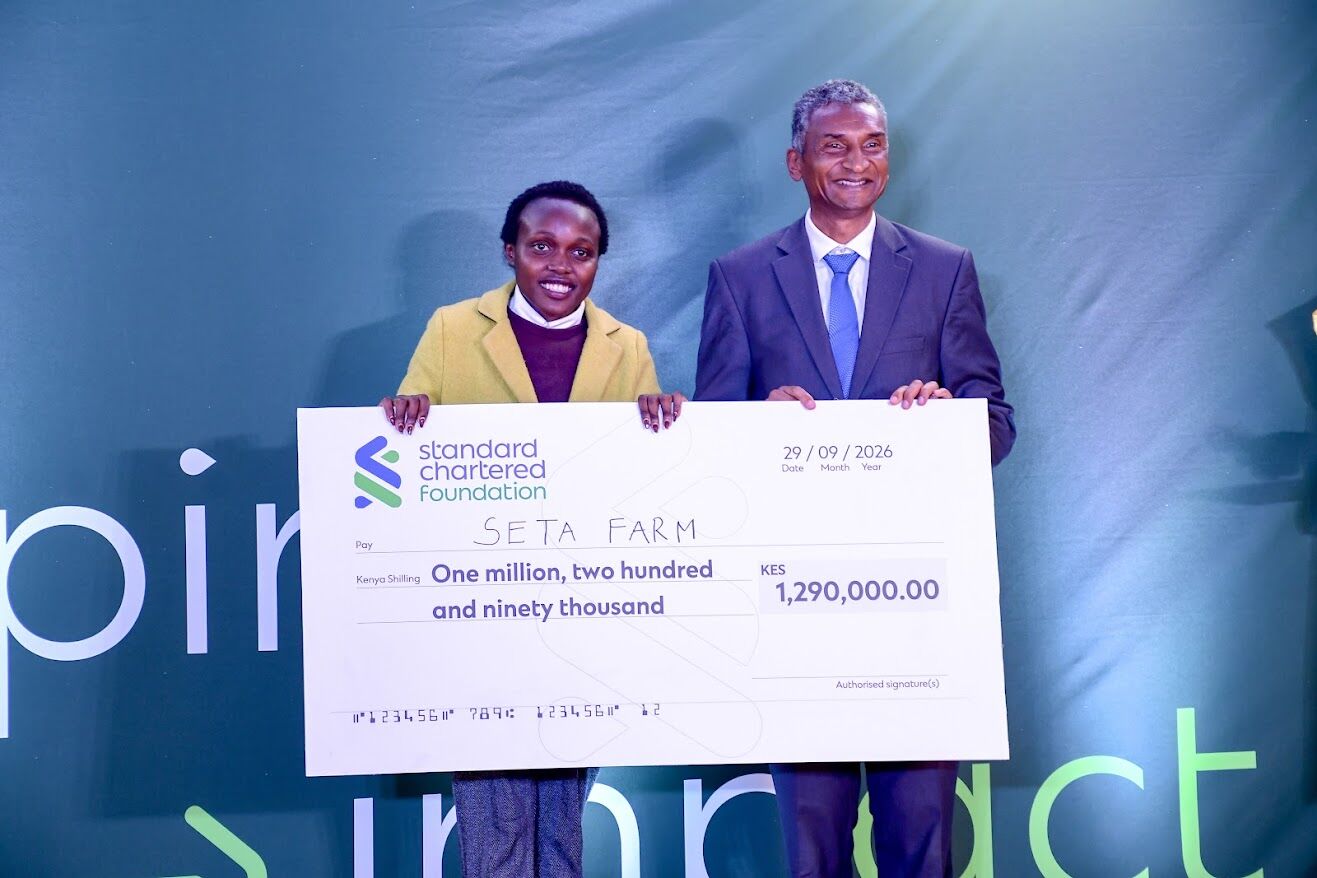 Seta Farm founder and Dr Vincent Ogutu hold a KES 1,290,000 Standard Chartered Foundation cheque on stage