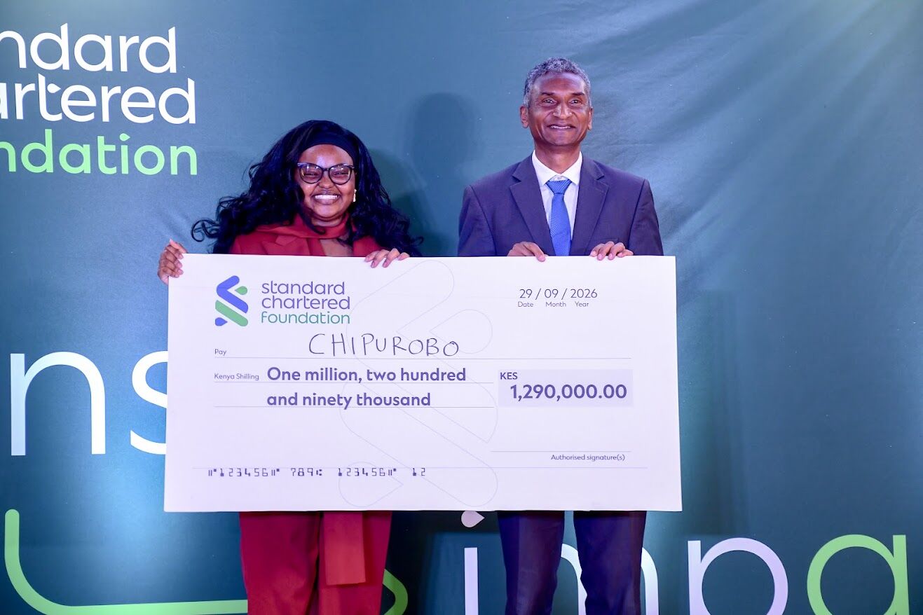 ChipuRobo co-founder holds a KES 1,290,000 Standard Chartered Foundation cheque on stage with a presenter