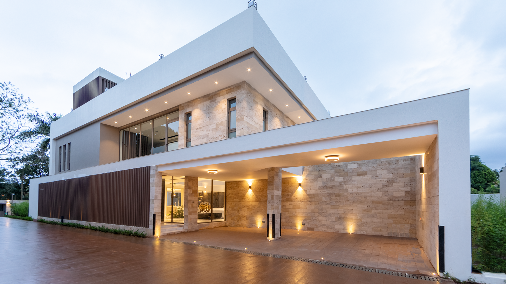 Exterior of Moments Villas at dusk showing its horizontal facade, travertine stone cladding and covered entrance courtyard.