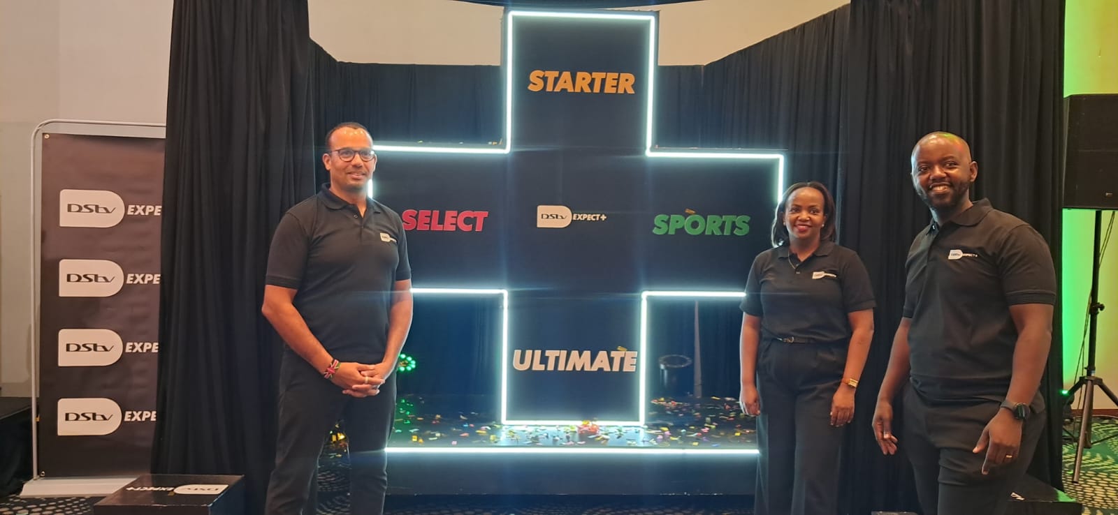 Nzola Miranda, Christine Warui and Elisha Kamau of MultiChoice Kenya stand beside the DStv Starter, Select, Sports and Ultimate display