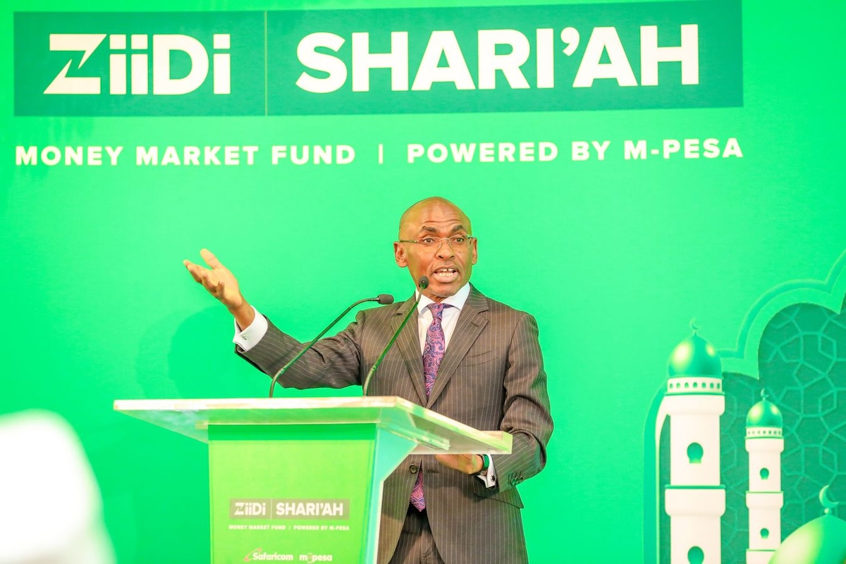 Safaricom CEO Peter Ndegwa speaks at a podium during the launch of Ziidi Shari'ah, a money market fund powered by M-Pesa, against a green backdrop.