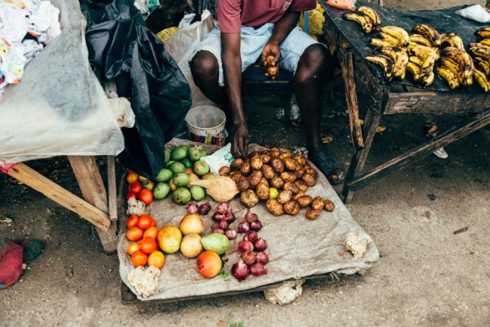 A fruit seller in one of Kenya's informal markets selling an assortment of fresh produce from potatoes, onions and tomatoes.
