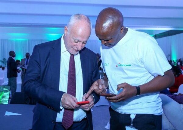 Michael Joseph, Safaricom Board member, shows a customer something on his mobile phone.