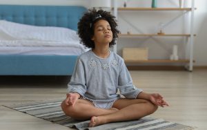 Child meditating on carpet in room