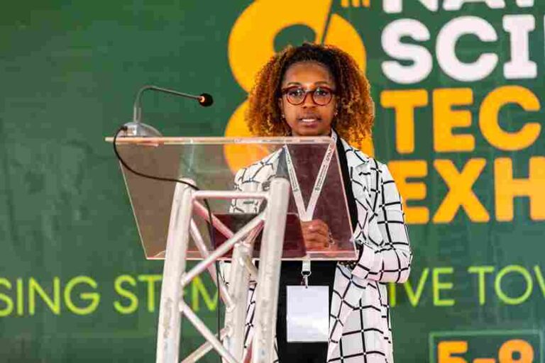 Jerusha Okubasu, HVC Postpay Manager at Safaricom, addressing attendees during the Opening Ceremony and dummy cheque handover at the National Science