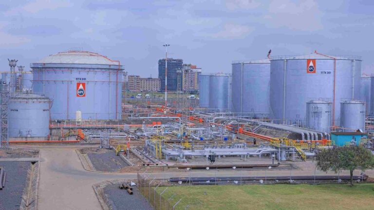 High Court Suspends Kenya Pipeline Privatisation Over Legal Challenge Industrial facility with large cylindrical KPC tanks and urban skyline. These tanks are interconnected by a dense network of pipes, staircases, and access platforms. In the backdrop, a mix of commercial and residential buildings suggests the site's integration within an urban or peri-urban environment. The layout implies petroleum or chemical storage operations at scale, emphasizing infrastructure complexity and proximity to strategic distribution corridors.