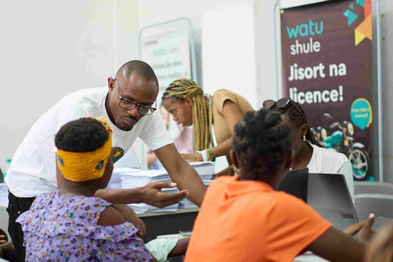 How Watu Is Redefining Engagement, Inclusion, and Clean Mobility in Kenya Group discussing smartphone features during Watu outreach