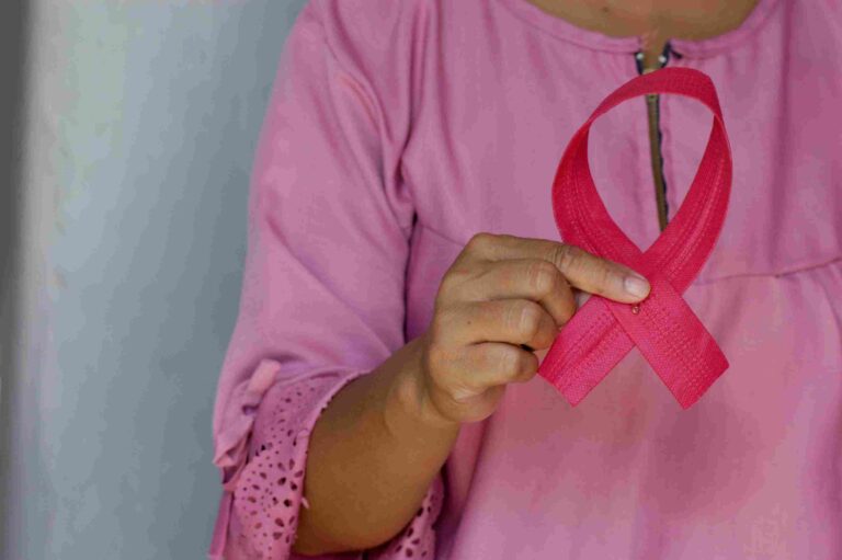 Woman holding pink ribbon for Breast Cancer Day awareness