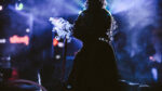 Silhouette of a woman smoking shisha against soft lighting