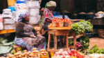 Woman vendor sitting among tomatoes, potatoes and vegetables at an East African open air market