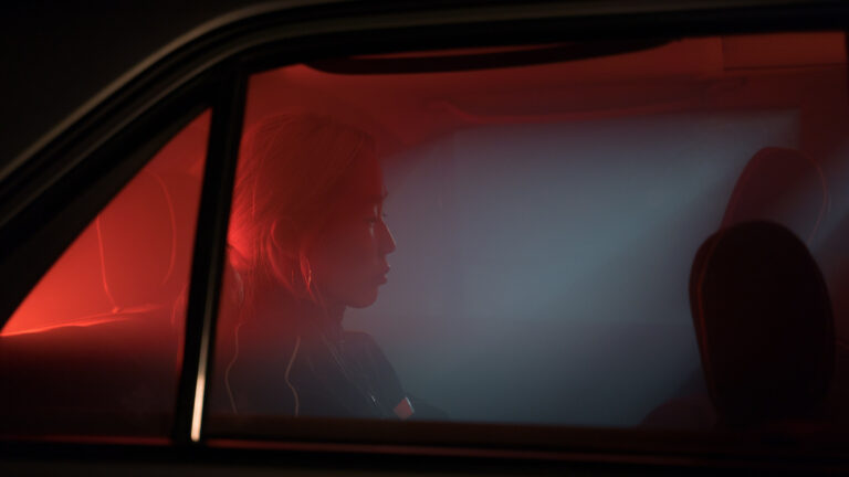 Why Some People Only Show Up When It Suits Them Woman with hoop earrings sitting quietly in the back seat of a car at night, lit by red light through the window, gazing away from the camera