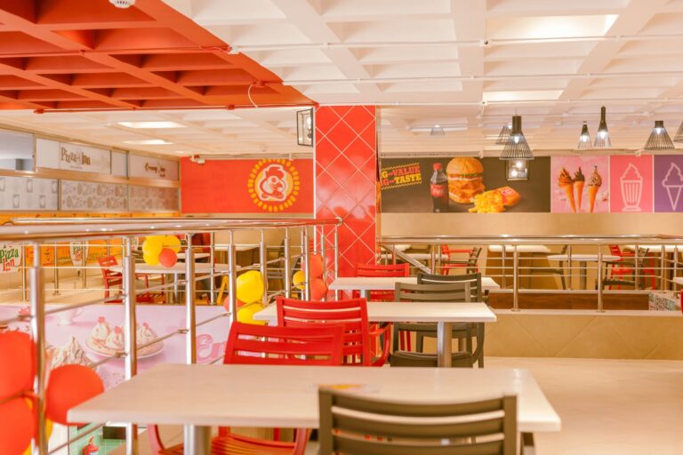 Dining area of the Chicken Inn 680 branch in Nairobi with red chairs, white tables and Pizza Inn and Creamy Inn counters.