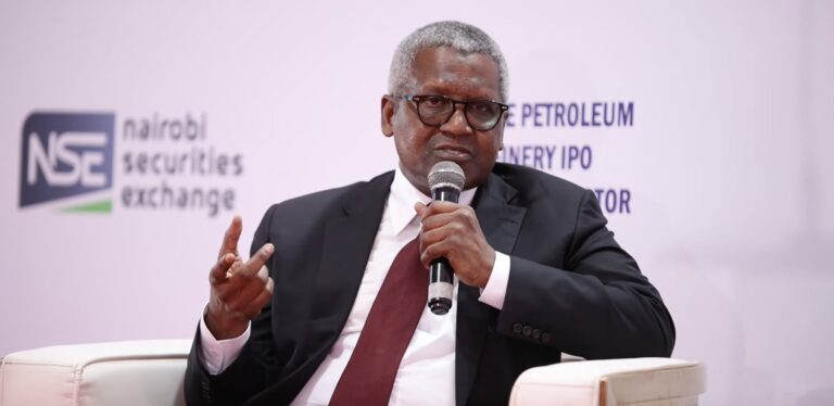 Dangote Says Court Order Will Not Stop Lamu Refinery Groundbreaking Aliko Dangote speaking into a microphone at a Nairobi Securities Exchange investor event, with an NSE logo and Dangote Petroleum Refinery IPO signage behind him.