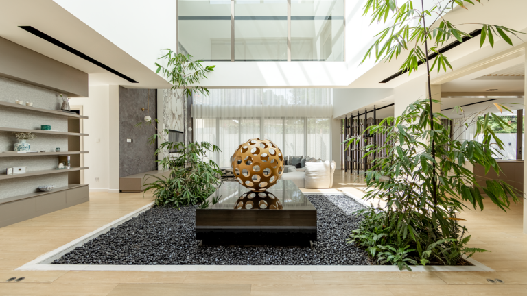 Double height living room at Moments Villas in Lavington with a glass wrapped bamboo courtyard and a sculptural gold coffee table.