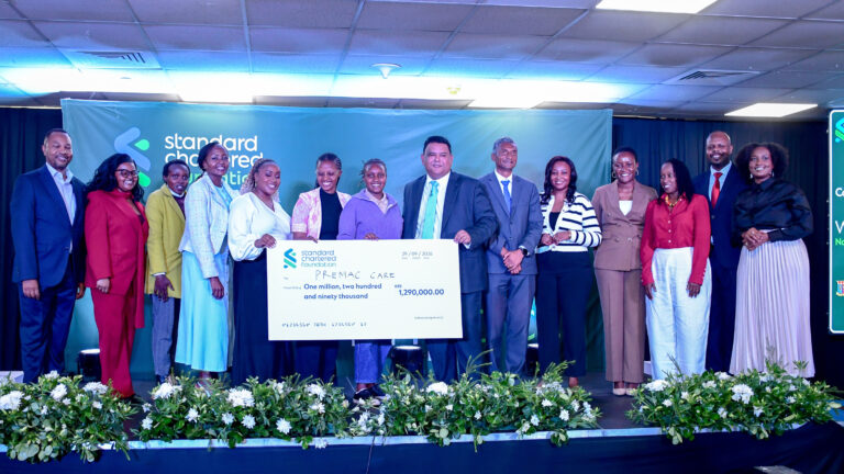 Standard Chartered awards KES 9 million to seven startups founded by women Women in Tech Kenya Cohort 9 winners and hosts on stage holding a KES 1,290,000 cheque made out to Premac Care