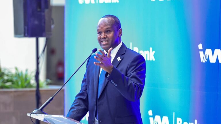 I&M Bank Confirms Abdi Mohamed as New CEO Man in a suit and tie speaks at a podium with a microphone, in front of an I&M Bank backdrop.