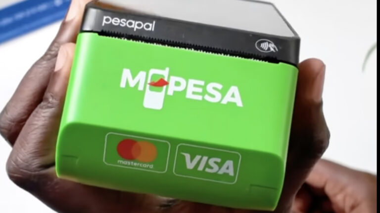 Safaricom and Pesapal Launch Tap and Scan Payments A hand holds a Pesapal point of sale terminal with a green M-PESA casing. The NFC contactless symbol sits on the top edge, and Mastercard and Visa logos appear on the front.